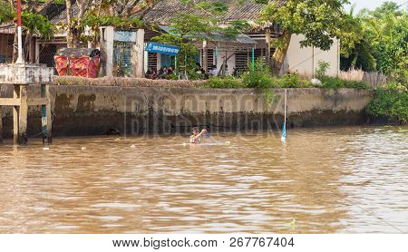 Cai Be, Vietnam-december 10, 2013. Local Vietnamese Man In The River Checks His Fishing Nets For The