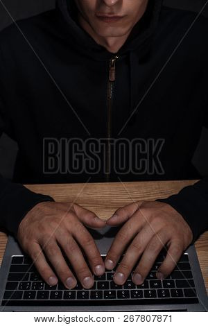 Partial View Of Hacker In Black Hoodie Using Laptop, Cuber Security Concept