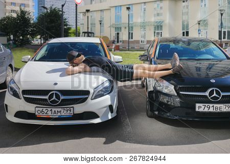 MOSCOW - JUN 20, 2018: Man (with MR) sleeps on two Mercedes Benz cars of Moscow carsharing company You drive, carsharing is system of short-term car rental