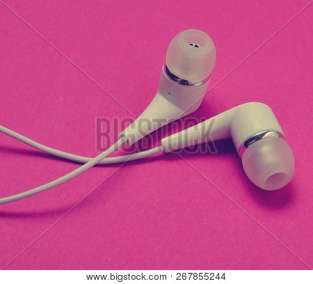 White Vacuum Headphones Close-up On A Pink Background.