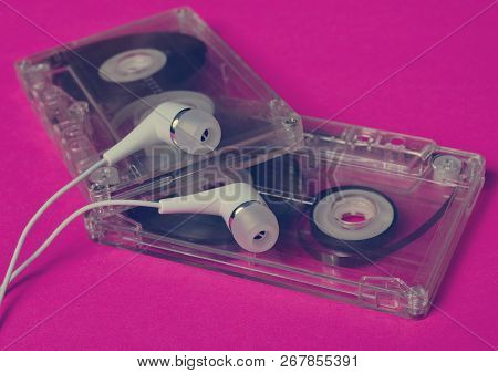 Retro Technology. Plastic Transparent Audio Cassette And White Vacuum Headphones On A Bright Pink Ba