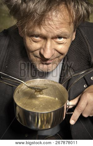 Ugly Pauper Man Living Outdoor Preparing Lentil Soup On Street