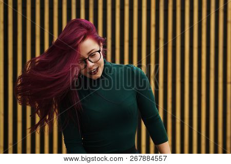 Cute Young Girl Dancing On Background Of Simple Geometric Pattern. Girl Has Eggplant Hair Flying In 