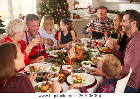 Multi-Generation Family Sitting At Table Enjoying Christmas Meal At Home Together