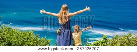 Mom And Son Travelers On A Cliff Above The Beach. Empty Paradise Beach, Blue Sea Waves In Bali Islan