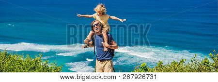 Dad And Son Travelers On A Cliff Above The Beach. Empty Paradise Beach, Blue Sea Waves In Bali Islan
