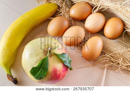 Six Eggs One Pomegrenate And One Banana On A Brown Sackcloth (burlap) And White Background- Traditio