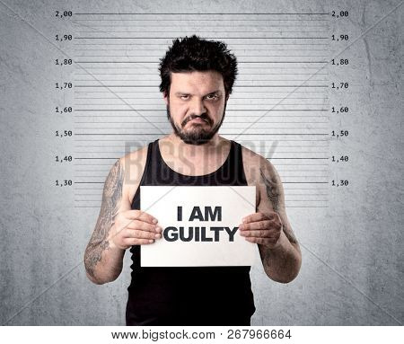 Caugth offender in front of a wall with table in his hand.