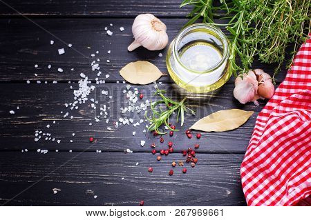 Bottle With Olive Oil With Herb And Spices Ob Black Wooden Background. Top View. Selective Focus. Pl