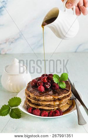 Pouring Maple Syrup Over Gluten Free Green Buckwheat Pancakes With Fresh Berries. Delicious Vegan Br