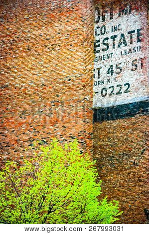 Fading Ad Fragment On A Red Brick Wall In New York City, New Yerk, United States Of America