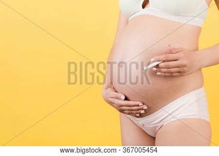Close Up Of Pregnant Woman In Colorful Underwear With A Cigarette Against Her Belly At Yellow Backgr