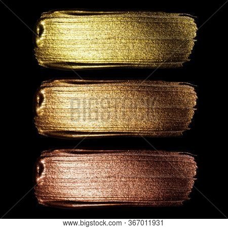 Creative brushstrokes of gold paint isolated on a black background. Gold paint texture.Acrylic gold paint. Smears of cosmetics, blush, highlighter, eye shadow, lipstick.