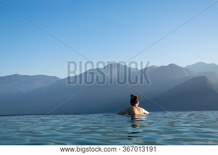Sexy Woman Relaxing In Infinity Swimming Pool   Looking At Stunning Mountain View At  Luxurious Reso