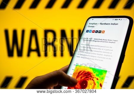 Mobile Phone Logged Into Photo Of Cyclone With Warning Background