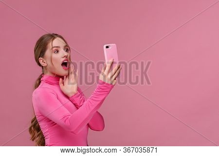 The Best Day Ever. Surpised Young Redhead Woman Holding Pink Smartphone, Smiling And Expressing Posi