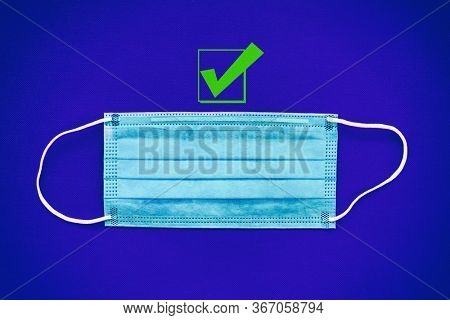 COVID-19 prevention by wearing a mask recommendation with green check mark as good choice to wear a face protection as preventive measure for coronavirus. Top view of surgical ear loop masks.