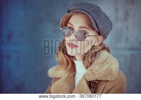 Romantic young woman with natural makeup and beautiful wavy blonde hair wearing outerwear and trendy sunglasses. Beauty, fashion concept. Optics and eyewear style. 