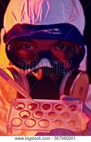 COVID-19 or 2019-nCoV. Close-up portrait of a scientist microbiologist in a protective PPE suit making a research on blood samples of infected people.