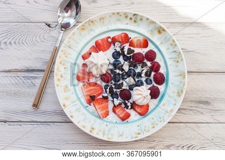 Oatmeal Porrige With Milk, Strawberries, Blueberries And Raspberries. Top View, Wooden Background.