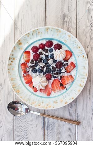 Oatmeal Porrige With Milk, Strawberries, Blueberries And Raspberries. Top View, Wooden Background.