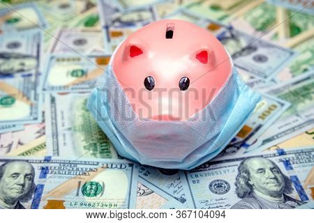 Piggy Bank In A Mask On A Background Of American Currency.the Concept Of Coronavrius Epidemic