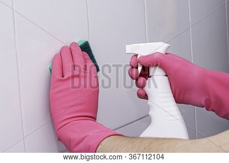 Bman In Rubber Household Gloves With A Sponge And Spray Washes A White Tiled Wall