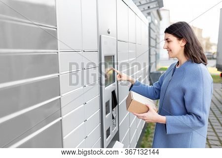 mail delivery and post service concept - happy smiling woman with box at outdoor automated parcel machine choosing operation on touch screen