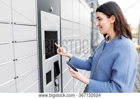 mail delivery and post service concept - happy smiling woman with smartphone choosing operation on outdoor automated parcel machine's touch screen