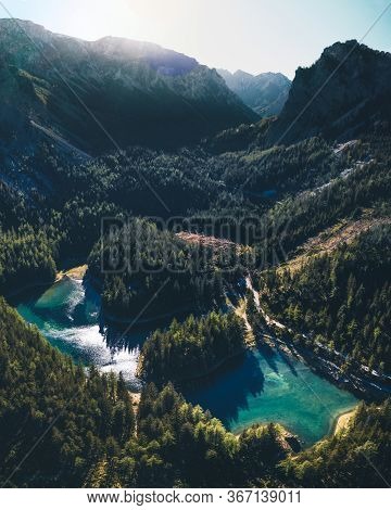 A Drone Shot Of An Alpine Valley In Austria. The Valley Has A Green Lake In The Middle. A Headland I