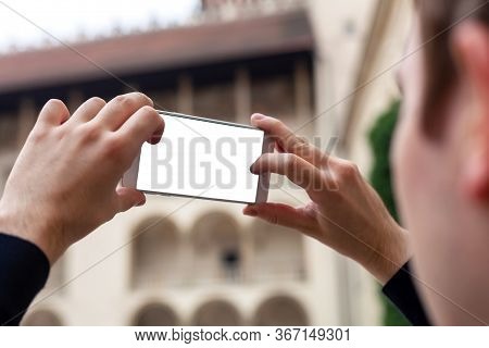 Young Man Taking Photos Of Architecture With His Smartphone Tapping The Shutter Button. Teen Holding