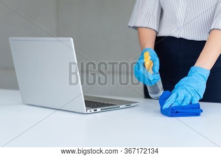 Business Woman Wearing Mask And Using Personal Sanitizer To Cleaning Her Table In Office To Keep Hyg