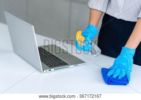 Business Woman Wearing Mask And Using Personal Sanitizer To Cleaning Her Table In Office To Keep Hyg