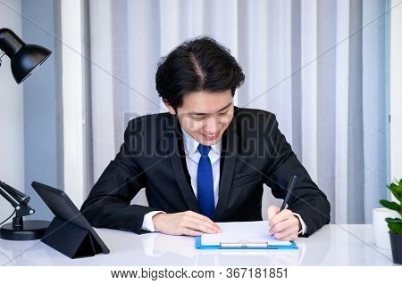 Asian Business Man Dringking Coffee Wearing Suit, Enjoying Watching Educational Webinar On Laptop Or
