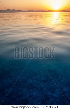 Stunning Seascape On Coral Under Clear Water. Sunset With A Reflection In The Water Taken With Slow 