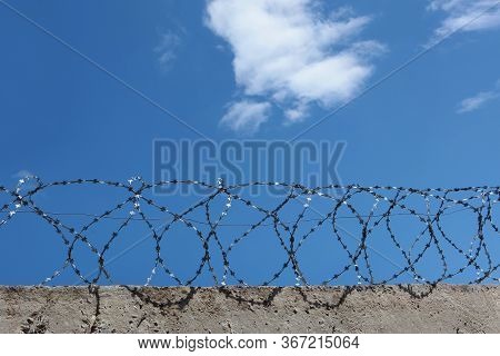 Barbed Wire Over A Concrete Wall. The Concept Of Incarceration. Photos Without People. Copy Of The S