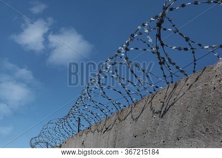 Barbed Wire Over A Concrete Wall. The Concept Of Deprivation Of Liberty Or Restriction Of Territory 