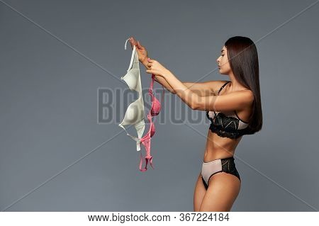 A Difficult Choice, A Beautiful Girl Chooses A Bra, Holding Bras Of Different Colors In Her Hands. G