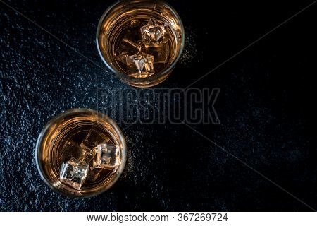 Whisky, Whiskey, Bourbon Or Cognac With Ice Cudes On Black Stone Table Top View