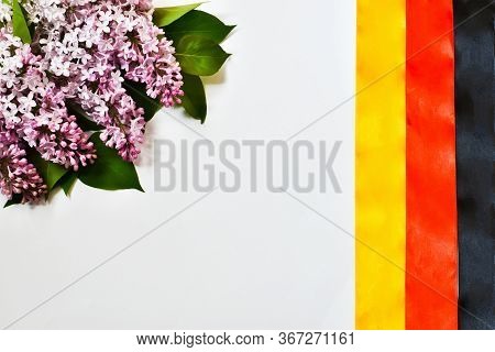 Happy German Unity Day, October 3. German National Flag Made Of Ribbons And A Bouquet Of Lilacs Isol
