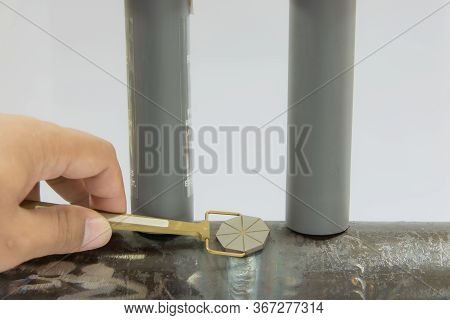 Human Hand Holding The Pie Field Indicator And Place On The Welding Between Two Permanent Magnet. Pi