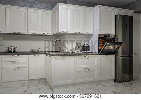 Electric appliances such as espresso coffee maker, sandwich maker and oven in modern minimalistic white kitchen interior