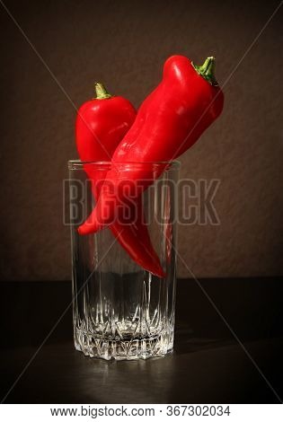 Still Life With Two Red Ramiro Peppers In The Glass Beaker Against A Low Key Background. Shallow Dep