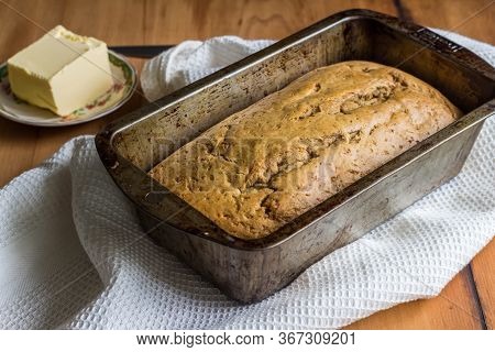 Banana Loaf In Loaf Tin With Butter On Kitchen Table