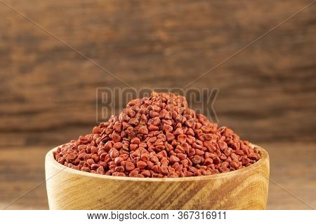 Organic Achiote Seeds - Bixa Orellana. Wood Background