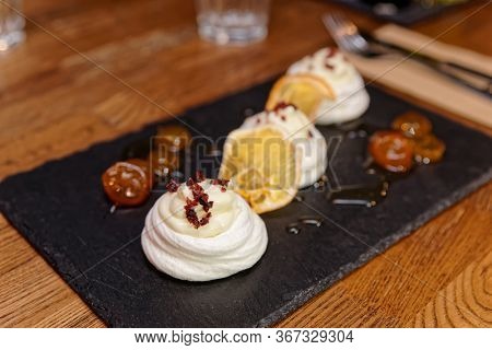 Meringue dessert with orange chips and sweet leechee jam on restaurant table