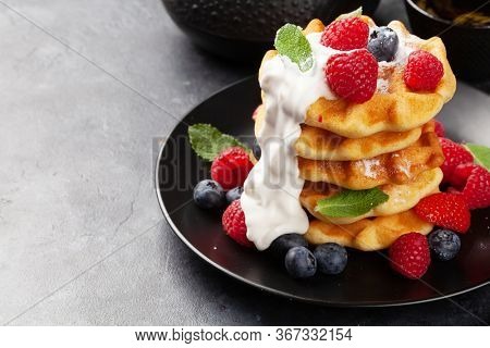 Delicious belgian waffles with ice cream and summer berries and breakfast tea. With copy space