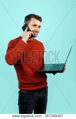 Confident Bearded Young Man In Casual Outfit With Notebook Or Computer Talk On Smartphone Over Cyan 