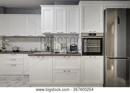 Electric appliances such as espresso coffee maker, sandwich maker and oven in modern minimalistic white kitchen interior