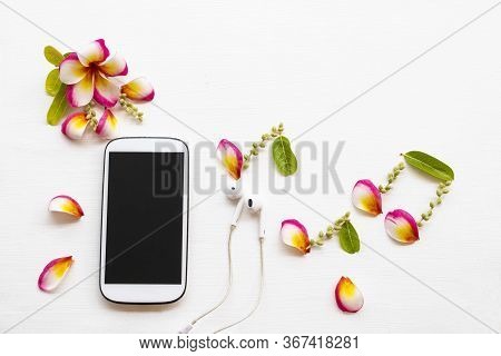 Mobile Phone ,earphone With Petal Coloful Flowrers Frangipani Arrangement Music Score Flat Lay Style